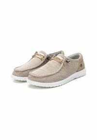 Zapatos casuales beige fabricados con material trenzado, con un acabado texturizado, puntera redonda y cordones beige. Suela de goma blanca y forro interior gris.