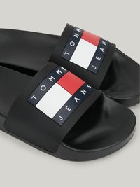 Chinelos pretos com uma tira larga que apresenta um logótipo em vermelho, branco e azul. Superfície lisa com uma palmilha texturizada para conforto.