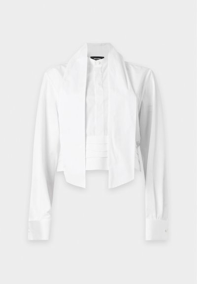 Chemise formelle blanche à manches longues avec un large col pointu en forme d’écharpe et un détail plissé à l’avant, présentée sur un fond gris clair.