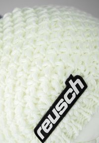 Knit beanie in light pastel green with textured pattern. Features a black logo patch with "reusch" prominently displayed.