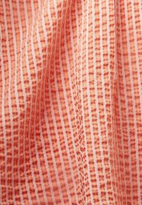 Textil mit einem strukturierten Muster aus wellenförmigen Streifen in sanften Pfirsich- und Weißtönen, mit abwechselnd erhobenen und flachen Abschnitten.