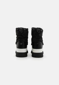 Bottes d'hiver noires avec un dessus rembourré, un motif subtil et une semelle blanche épaisse. Comprend des lacets ajustables et des accents sur les côtés.