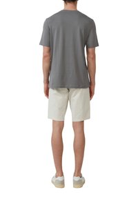 Grijze T-shirt met korte mouwen en een ronde halslijn, gecombineerd met beige shorts. De schoenen hebben een witte basis met grijze accenten en een tan kleurige zool.