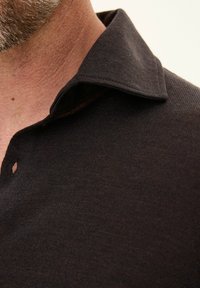 Ciemnobrązowa koszulka polo z teksturowanej tkaniny, z kołnierzykiem, częściowym zapięciem na guziki oraz delikatnymi detalami z dzianiny.