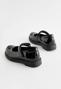 Scarpe Mary Jane in pelle verniciata nera con punta arrotondata, cinturino con velcro e suola in gomma testurizzata. Finitura liscia senza decorazioni.