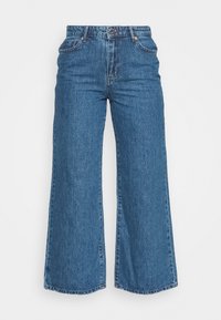 Bredvid ben, högmidjade denimjeans i medelblått med en viss blekning, utrustade med fem fickor och koppardetaljer.