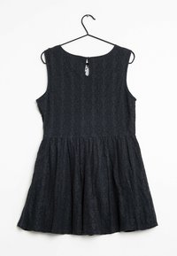 Schwarzes Spitzenkleid mit weit auslaufendem Rock, ärmellosem Design, rundem Ausschnitt und Schlüsselaugen-Detail im Rücken. Strukturiertes Muster über den gesamten Stoff.