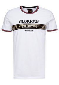 Valkoinen puuvillainen T-paita, jossa on pyöreä kaula-aukko. Paidassa on musta "GLORIOUS" -teksti ja kultainen geometrinen kuvio rinnassa. Punaiset yksityiskohdat hihoissa.
