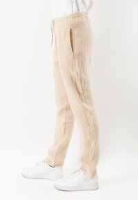 Lichtbeige linnen broek met een losse fit, frontzakken en een elastische tailleband. Gekocht met witte sneakers voor een casual uitstraling.