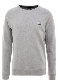 Grå sweatshirt gjord av mjukt material med rund halsringning och ribbad mudd. Har en liten svart rektangulär logotyp på bröstet.