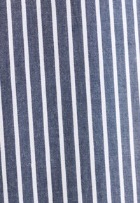 Rayures verticales bleu marine et blanches sur tissu texturé, espacées de manière uniforme avec un motif tissé subtil visible.