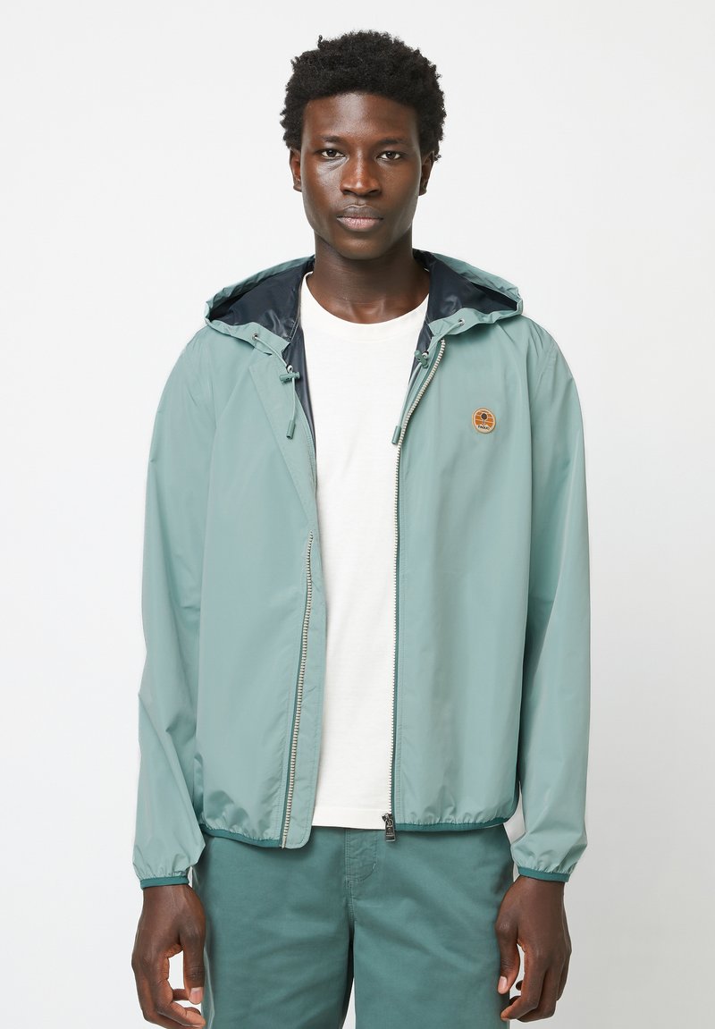 Lightweight, mint green zip-up jacket with adjustable hood, elastic cuffs, and a logo patch on the chest; smooth texture and casual fit.