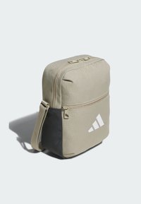 Svetlohnedá taška cez rameno s čiernym dnom, so zipsom a bielym logom. Obdĺžnikový tvar s textúrovaným povrchom a nastaviteľným popruhom.