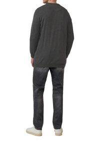 Koolgrijze gebreide trui met een ronde halslijn, lange mouwen en een geribde zoom, gecombineerd met vervaagde donkere jeans en witte sneakers.