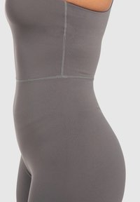 Bodysuit ajustado de color gris, fabricado con un tejido elástico, que presenta un diseño sin costuras, una textura suave y detalles de costura visibles a lo largo de los lados.