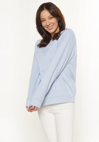 Felpa azzurra chiara con maniche lunghe e polsini a costine, realizzata in un materiale morbido. Caratterizzata da una vestibilità comoda e un collo rotondo.