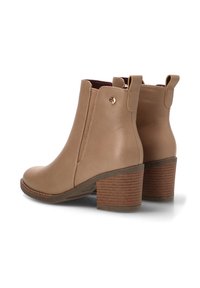 Botas de cuero beige hasta el tobillo con punta redonda, cremalleras laterales y un tacón apilado texturizado. Presentan pequeños acentos de logo en la parte trasera.