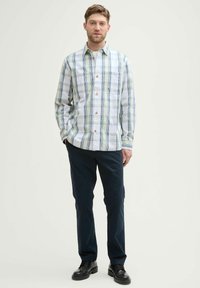 Overhemd met knoopsluiting, gekenmerkt door een groen en blauw ruitpatroon op wit. Slim fit met een borstzak, gecombineerd met donkergekleurde broeken en zwarte schoenen.