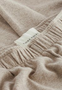 Světle hnědá látka s jemným, texturovaným povrchem, s elastickým pasem a štítkem s nápisem "Laura Ashley".