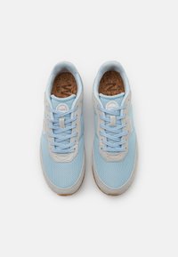 Blå mesh-sneakers med ljusgrå detaljer, rund t å och korkinsatser. Har platta skosnören och en strukturerad gummisula.