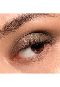 Close-up van een oog met glanzende olijfgroene oogschaduw, lange wimpers en een lichtbruin iris. De huidtint is egaal en glad.