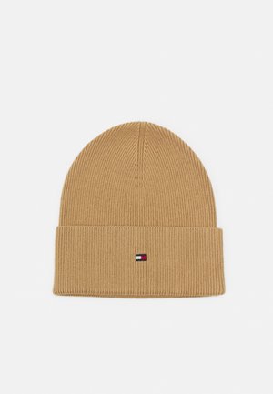 Bonnet en maille côtelée beige avec revers plié présentant un petit patch logo rectangulaire rouge, blanc et bleu centré sur le revers.