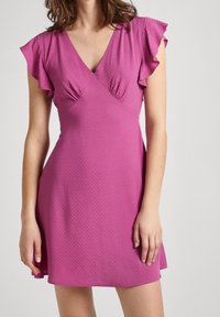 Sydd rosa klänning med korta volangärmar, v-ringning, textil med struktur och utsvängd fåll, som erbjuder en lätt och avslappnad design.