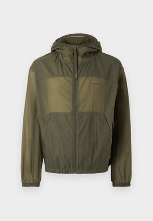 Lightweight olive green hooded jacket with a zip front, elastic cuffs, and two front pockets; features a textured fabric and logo detail.