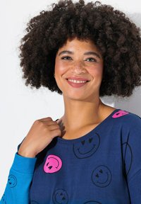 Camicia blu a maniche lunghe con stampe di faccine sorridenti rosa e nere; tessuto di cotone morbido con vestibilità comoda e scollo rotondo.