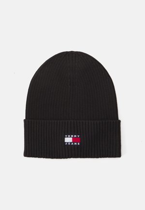 Gorro de punto negro con textura de canalé. Presenta un dobladillo plegado y un pequeño logotipo bordado en rojo, blanco y azul en la parte frontal.