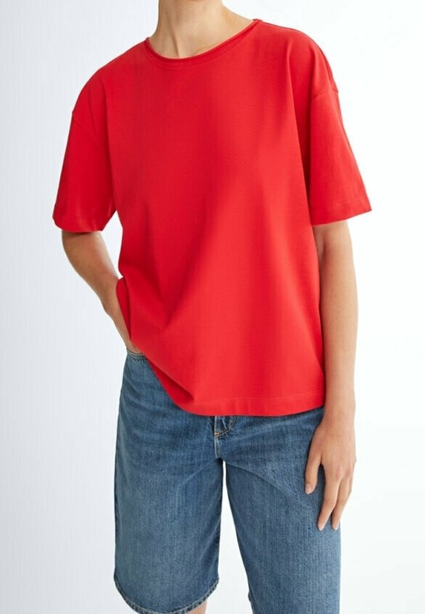 T-shirt rouge à manches courtes, coupe décontractée, en coton doux, avec un col rond et une texture lisse, assorti à un short en jean.