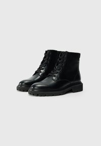 Svarta läderankelboots med snörning fram, rund tå och tjock gummisula med struktur och en robust mönstring.