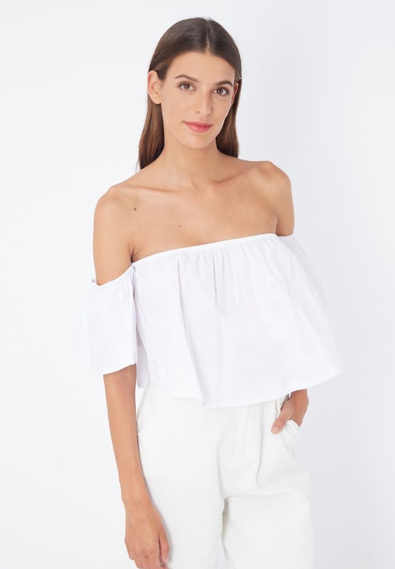 Top corto blanco sin mangas con escote fruncido y mangas cortas acampanadas, combinado con pantalones blancos holgados. Textura suave.