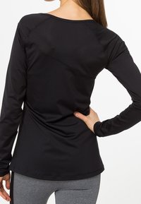 Maglia nera a maniche lunghe con scollatura rotonda e dettagli delle cuciture, realizzata in un tessuto liscio ed elasticizzato, caratterizzata da una silhouette aderente.