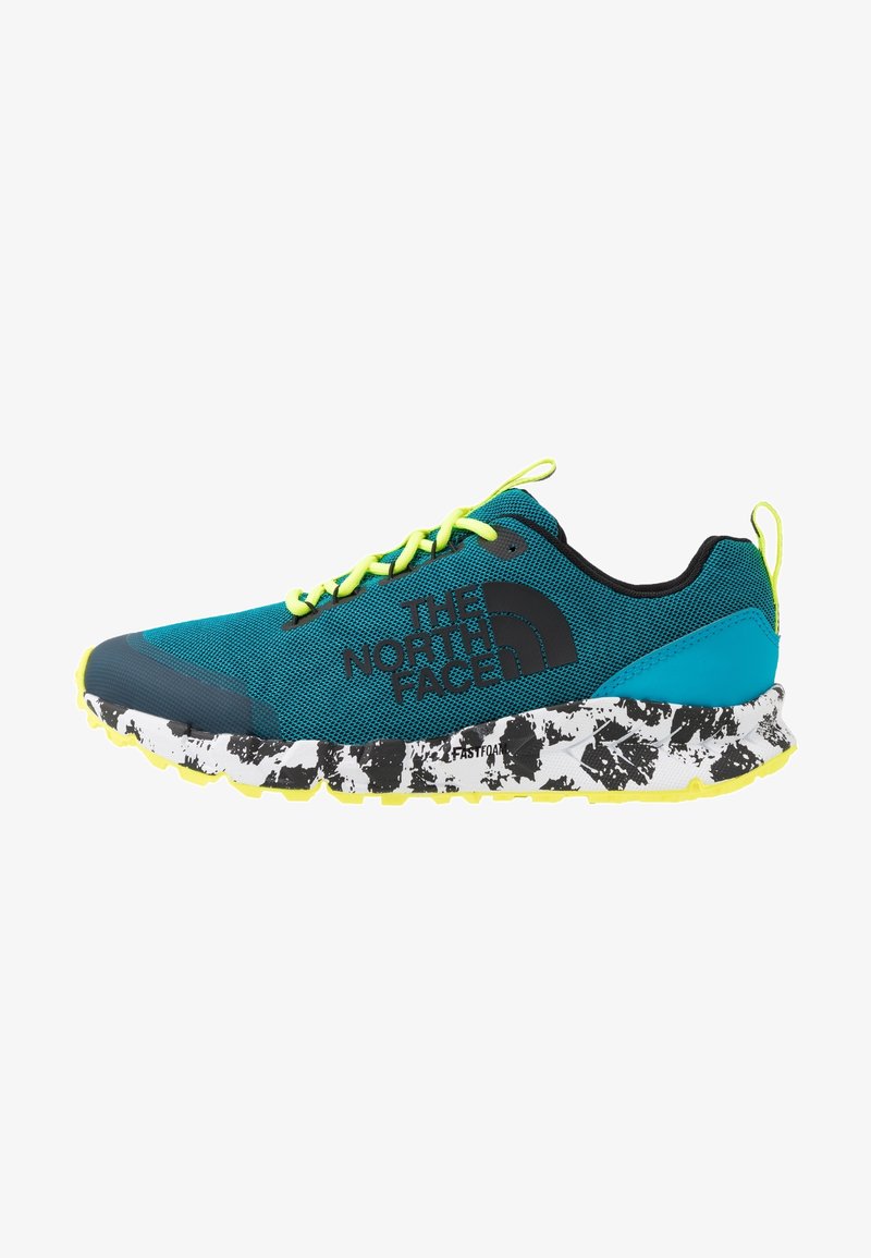 Chaussure de sport bleue avec des lacets jaunes, une tige texturée et un logo noir. Elle présente une semelle blanche et noire à motifs. Conception légère.