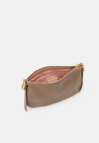 Brun læderpung med en glat tekstur, guld lynlås og pink indre foring; har sidelisserdetalje og en struktureret form.