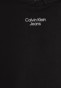 Černá mikina s měkkou texturou, s bílým logem "Calvin Klein Jeans" na hrudi. Klasický střih s kapucí.
