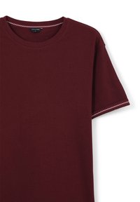 T-shirt in cotone corto di maniche color bordeaux con coltondo e cuciture bianche a zigzag sui bordi delle maniche e sul colletto.