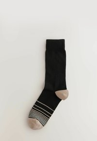 Sosete negre cu un tiv ridat, vârf bej și un model în dungi pe talpă. Realizate dintr-un material neted și moale.