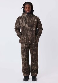 Completo giacca e pantaloni cargo a motivi marrone e crema, realizzato in tessuto testurizzato con cappuccio, ampie tasche e una vestibilità comoda. Calzature nere.