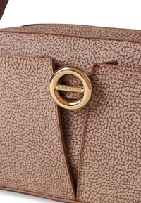 Dettaglio ravvicinato di una borsa beige-marrone con trama, dotata di una chiusura circolare dorata incisa "Borbonese" e con cuciture dettagliate lungo i bordi.