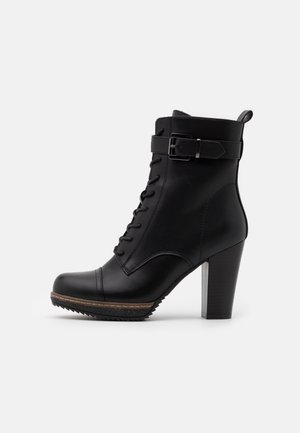 Bottine noire en cuir à talon bloc, devant lacé, bride latérale à boucle et semelle texturée sur fond blanc.