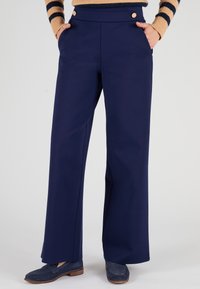 Navy-wijd been broek met een gladde textuur, voorzien van twee gouden knopen op de tailleband en zijzakken. Gepaard met navy instappers.