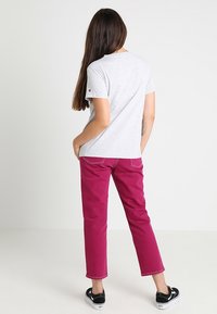 Grijs katoenen T-shirt met korte mouwen, gecombineerd met fuchsia broek en zwarte sneakers. Achteraanzicht, met een eenvoudig ontwerp en stikseldetails.