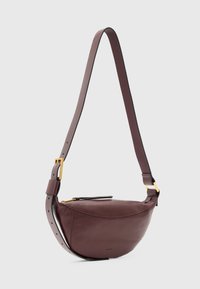 Borsa a tracolla in pelle bordeaux con forma curva, tracolla regolabile, dettagli in metallo dorato e cuciture sottili. Texture liscia.