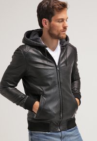 Giubbotto bomber in pelle nera con cappuccio grigio, chiusura zipper frontale, polsini a coste e tasche laterali. Texture liscia con elementi di design eleganti.