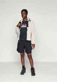 Világosszürke polárdzseki fekete kiegészítőkkel, sötétkék póló piros grafikával, fekete cargo nadrág és sötét túrabakancs.