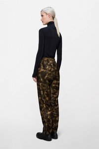 Μαύρο τοπ με μακριά μανίκια συνδυασμένο με παντελόνι με ελαστική μέση και χαλαρή εφαρμογή σε καφέ και μαύρο μοτίβο ταΐ-ντάι· λείο υλικό, casual σχεδιασμός.