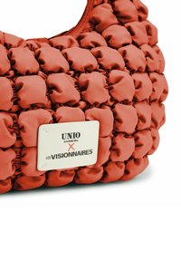 Borsa a spalla rossa imbottita con design in tessuto arricciato, con etichetta bianca con testo nero che recita: "UNIO HAMBURG X LES VISIONNAIRES."