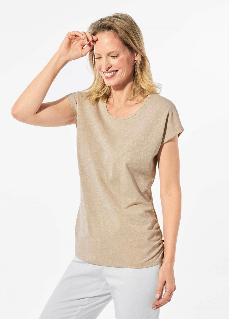 Korte mouw, beige top gemaakt van lichte stof met een gladde textuur. Kenmerkt zich door een ronde halslijn en plooidetails aan de zijkanten.